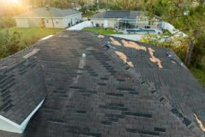 Storm Damage Roof Repairs in Hammond, LA by Pride Roofing LLC. Image of a damaged house roof with missing shingles after a storm, indicating the need for roof restoration.