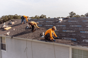 Storm-Proof roofing by Pride Roofing LLC in Hammond, LA: Workers installing new roofing shingles on a house, showcasing the process of storm-proofing a roof to withstand Louisiana’s extreme weather conditions, including hurricanes and heavy rains.